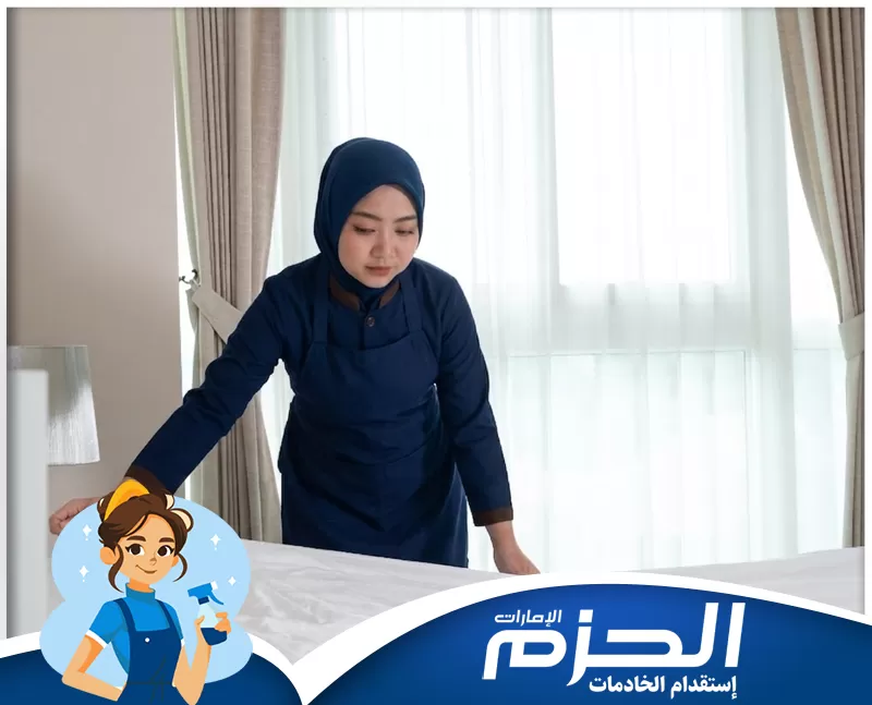 خادمة اندونيسية عجمان 0558713599 شركه الحزم. عاملة منزلية أثناء أداء مهامها داخل غرفة مرتبة، في صورة تعكس التنظيم والاهتمام بالتفاصيل في الخدمة المنزلية.