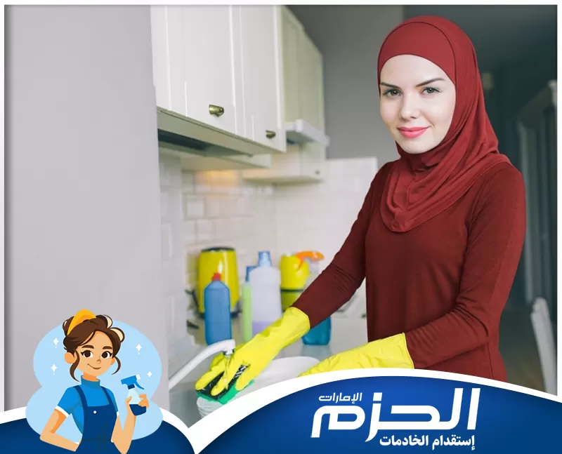 خادمات منازل عجمان 0558713599 شركة الحزم عاملة منزلية أثناء تنظيف المطبخ في صورة تعكس العناية بالنظافة اليومية وترتيب المساحات المنزلية بشكل منظم.
