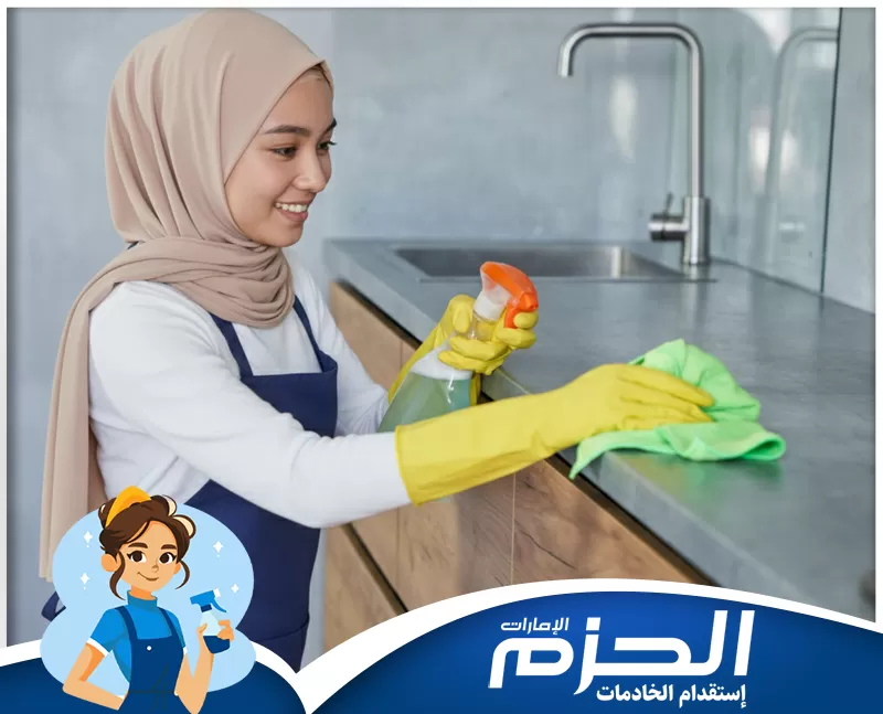 استقدام خادمات منازل راس الخيمة للتواصل 0558713599. عاملة منزلية تقوم بتنظيف سطح المطبخ باستخدام بخاخ وقطعة قماش، مع اهتمام واضح بترتيب ونظافة المساحات اليومية.